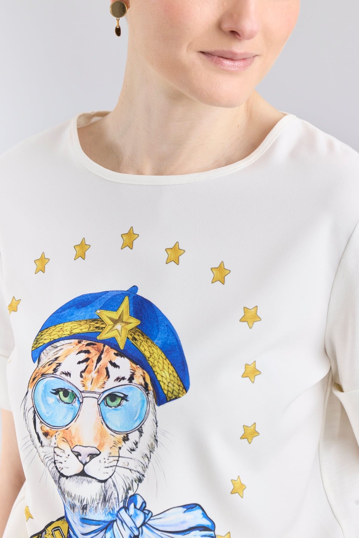 Camiseta blanca con botones dorados en las mangas y estampado de tigre con boina azul de The Extreme Collection