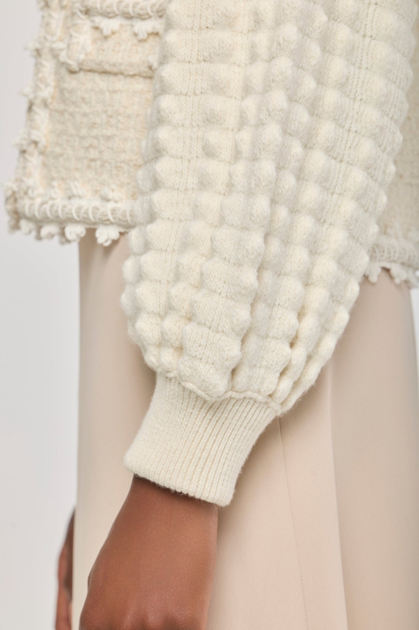 Cárdigan estructurado blanco de punto para mujer con estética estilo tweed, mangas abullonadas y ribetes detallados.