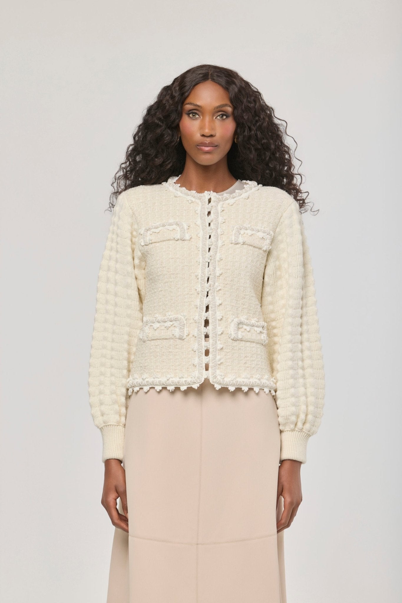 Cárdigan estructurado blanco de punto para mujer con estética estilo tweed, mangas abullonadas y ribetes detallados.