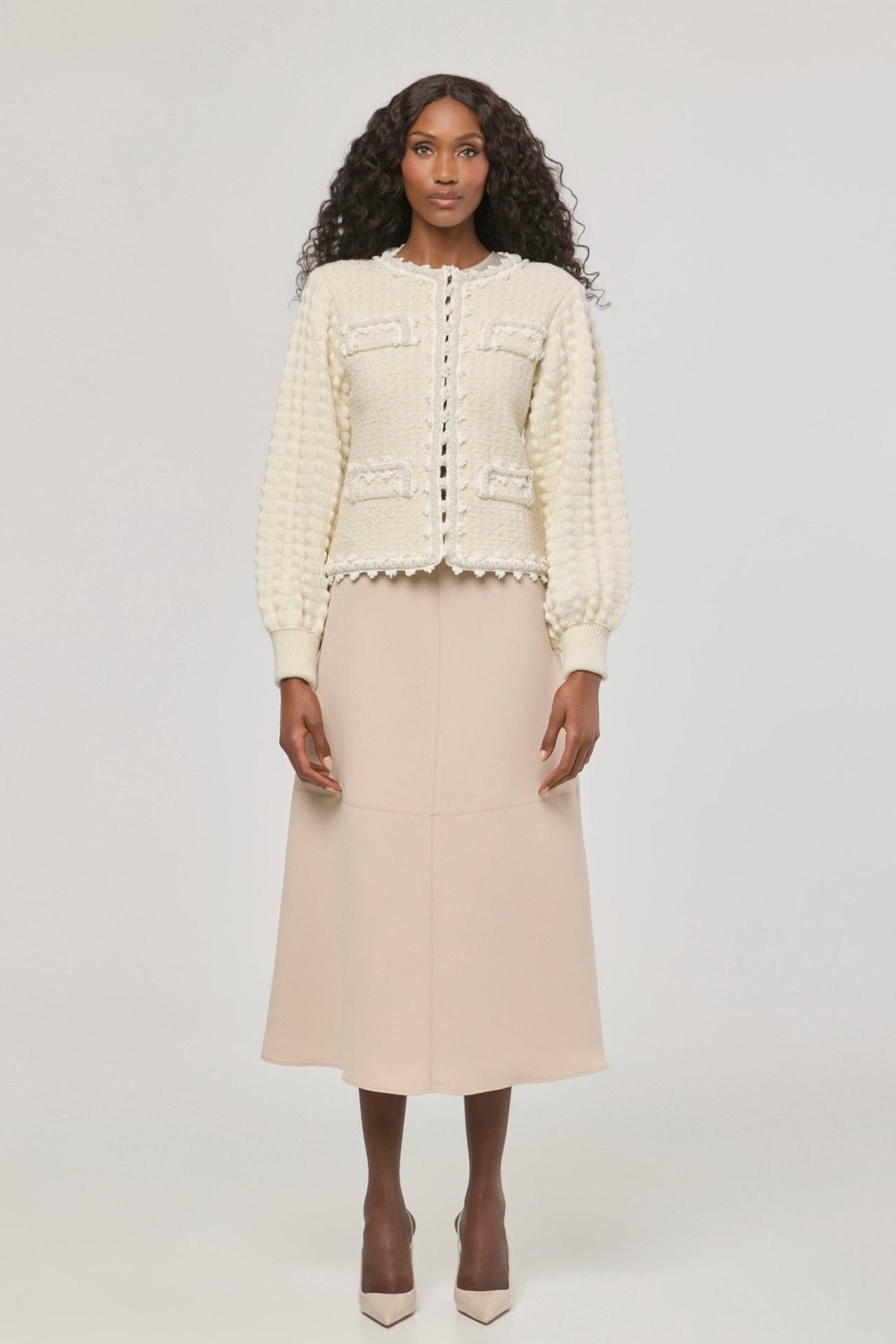 Cárdigan estructurado blanco de punto para mujer con estética estilo tweed, mangas abullonadas y ribetes detallados.