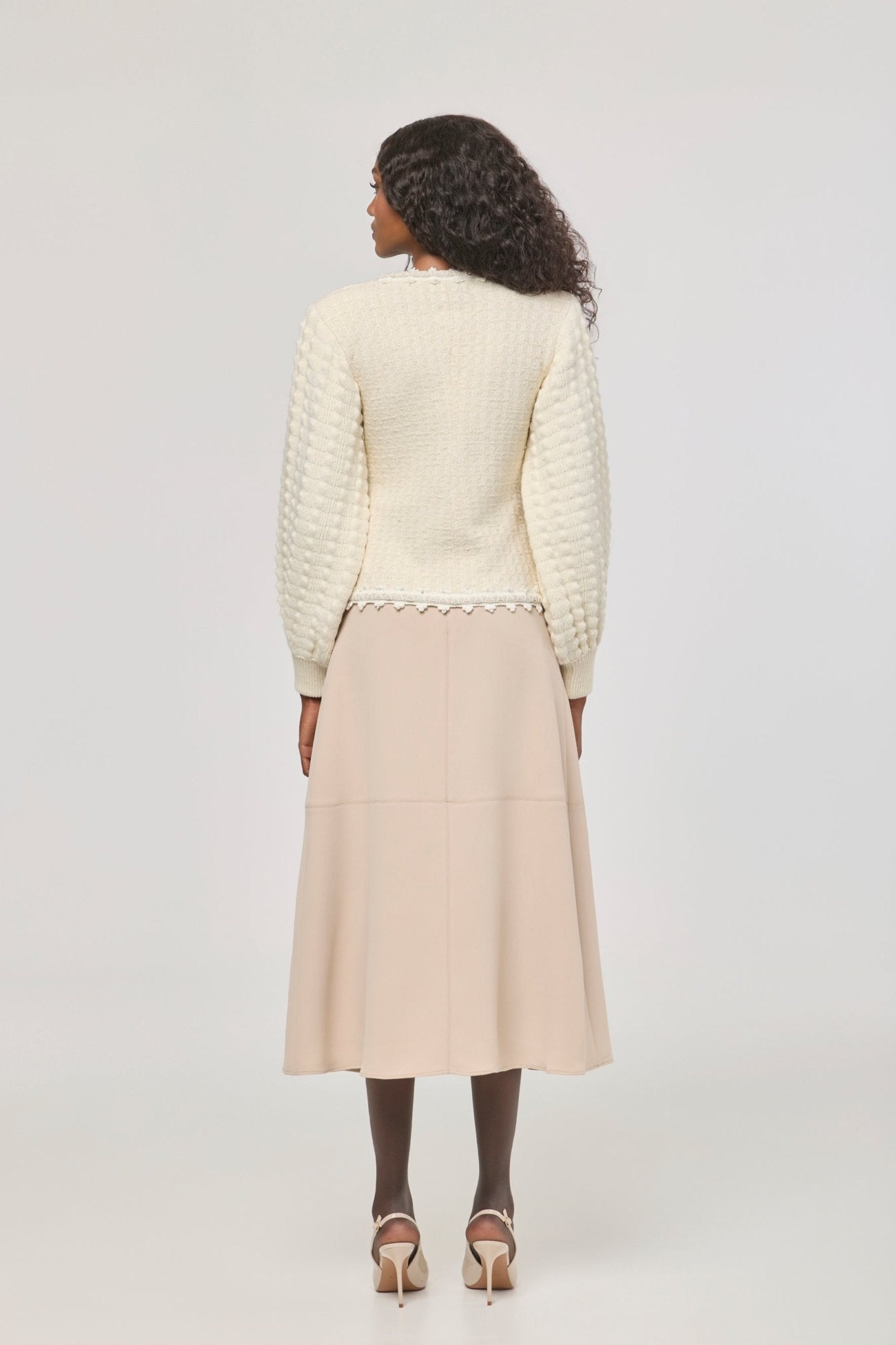 Cárdigan estructurado blanco de punto para mujer con estética estilo tweed, mangas abullonadas y ribetes detallados.