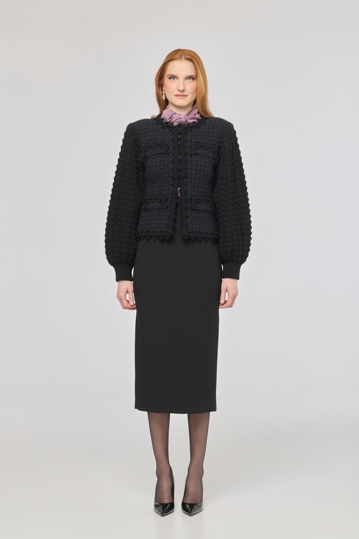 Cárdigan estructurado negro para mujer con estética estilo tweed, mangas abullonadas y cierre mediante corchetes.