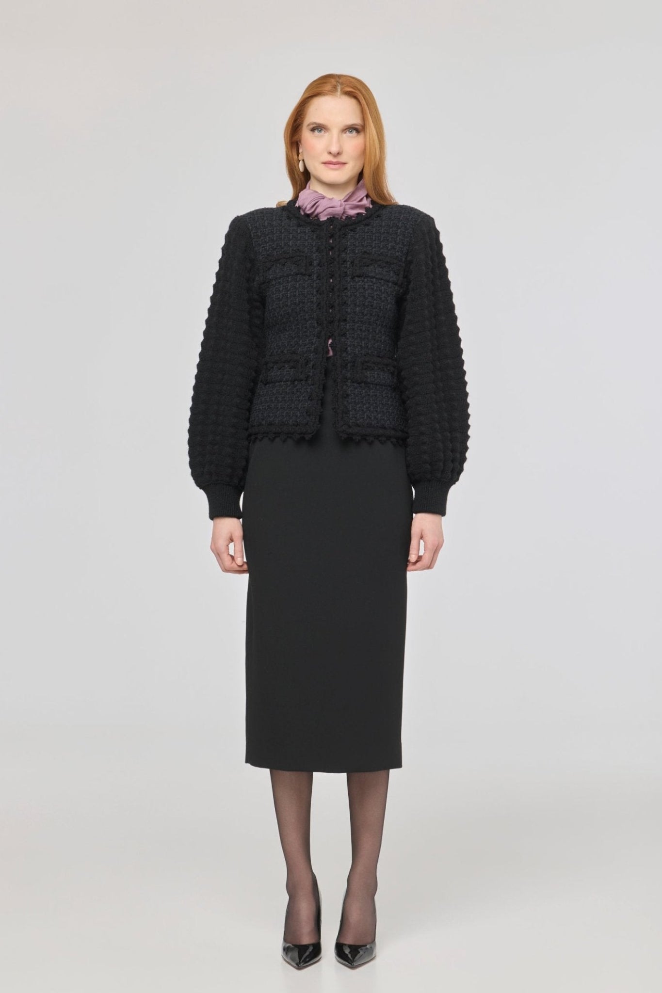 Cárdigan estructurado negro para mujer con estética estilo tweed, mangas abullonadas y cierre mediante corchetes.
