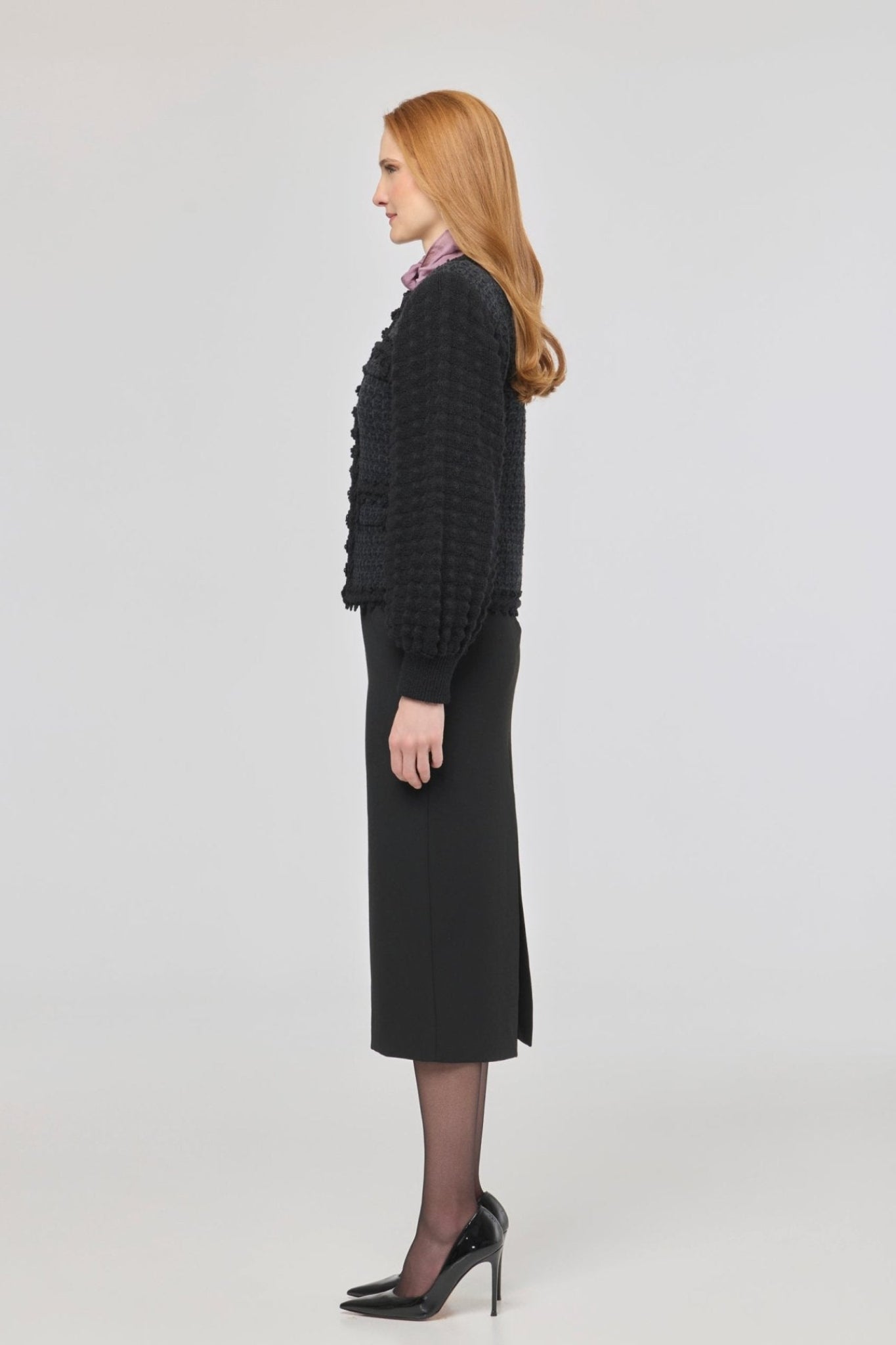 Cárdigan estructurado negro para mujer con estética estilo tweed, mangas abullonadas y cierre mediante corchetes.