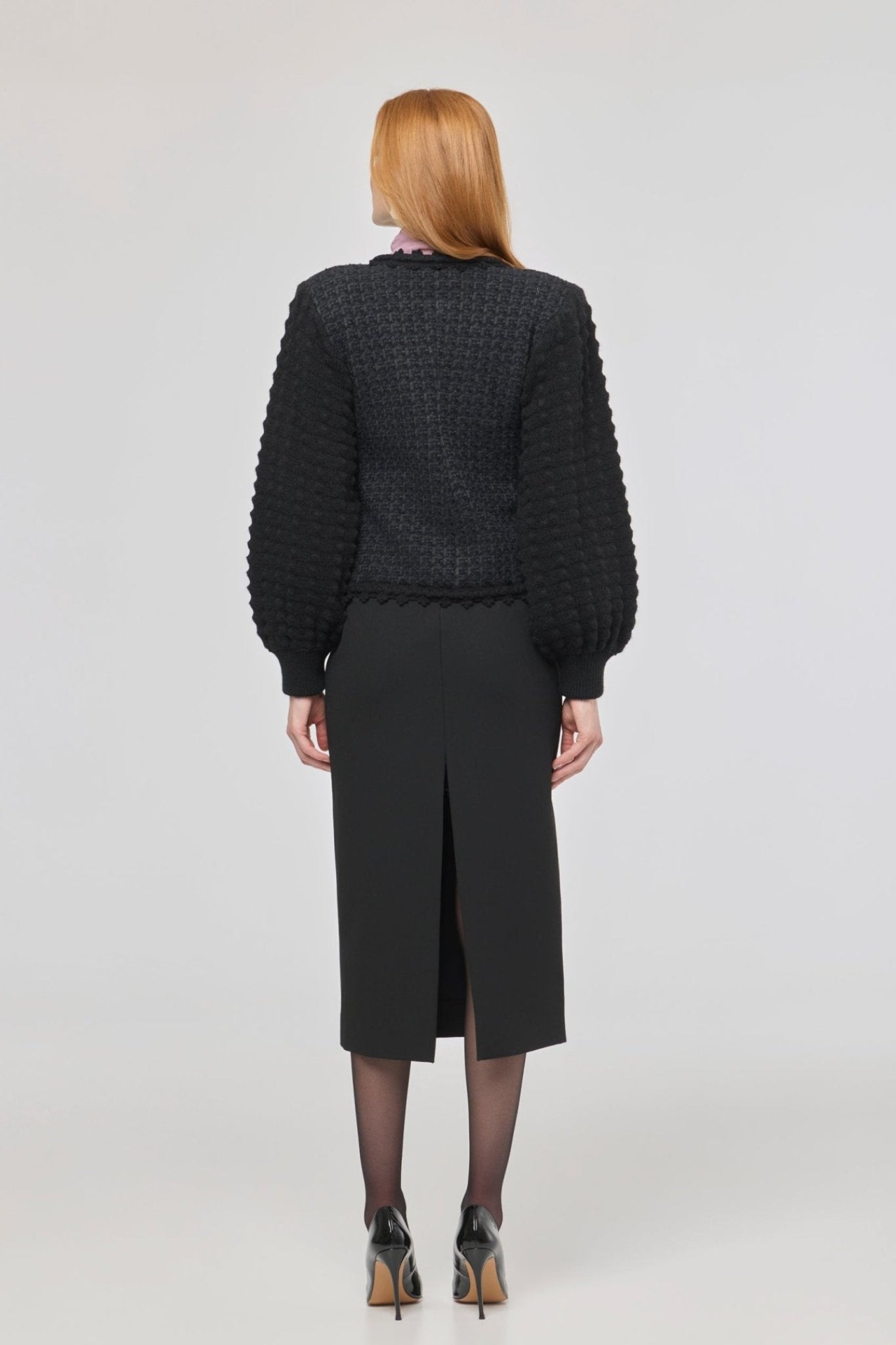 Cárdigan estructurado negro para mujer con estética estilo tweed, mangas abullonadas y cierre mediante corchetes.