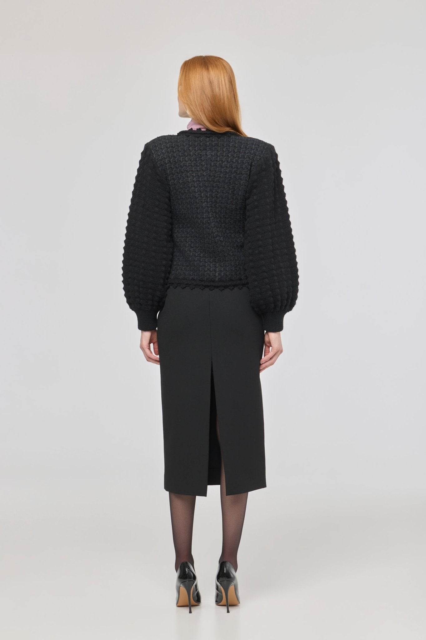 Cárdigan estructurado negro para mujer con estética estilo tweed, mangas abullonadas y cierre mediante corchetes.