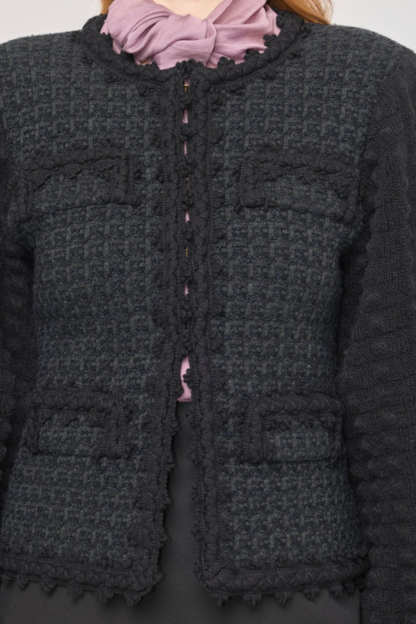 Cárdigan estructurado negro para mujer con estética estilo tweed, mangas abullonadas y cierre mediante corchetes.