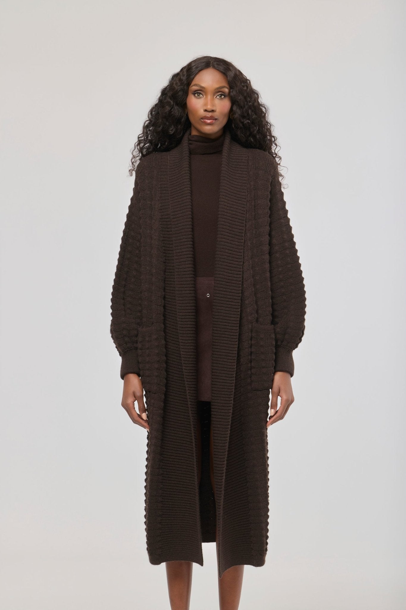 Cárdigan largo marrón de punto para mujer con mangas de textura geométrica y diseño minimalista.