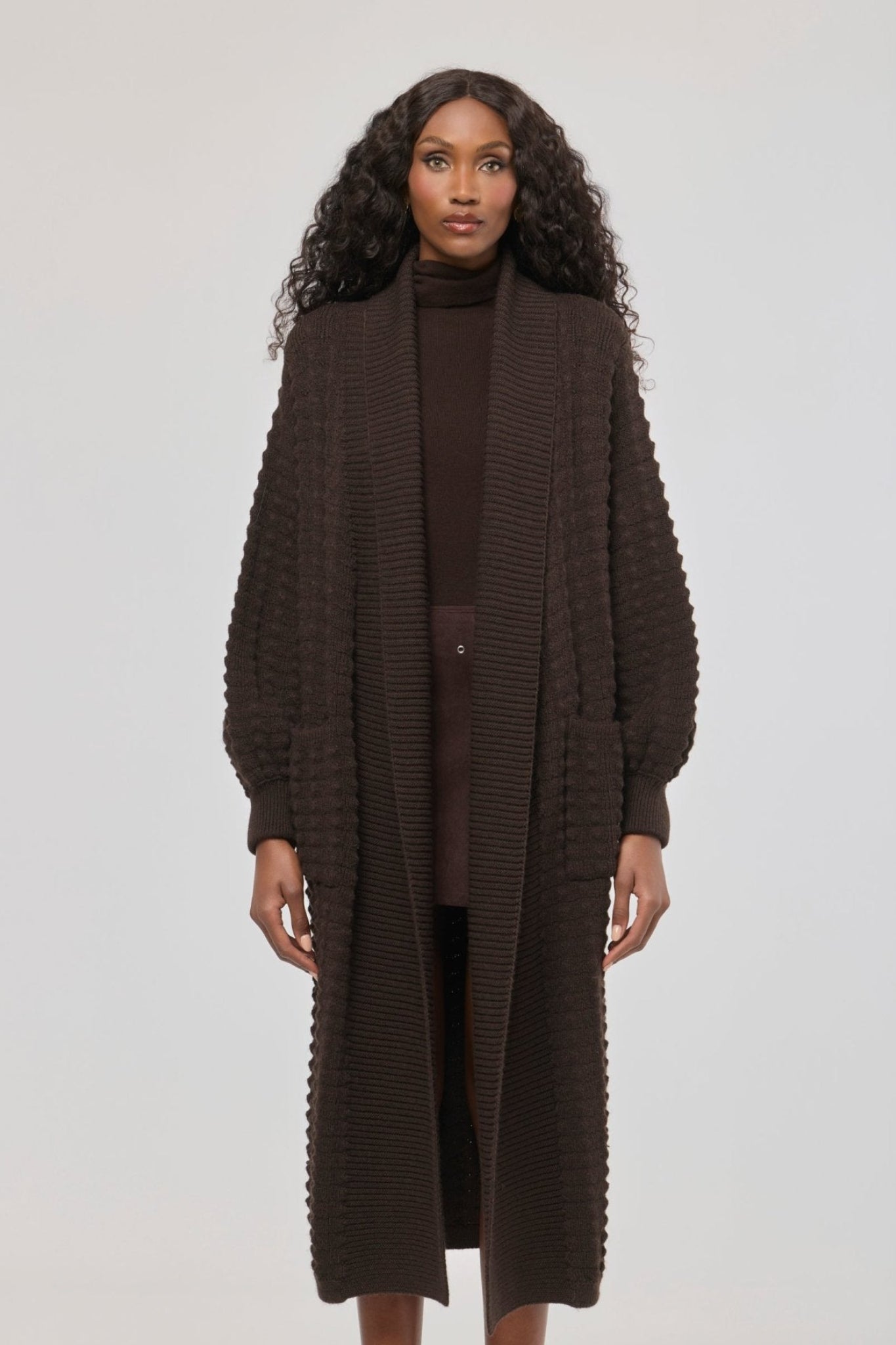 Cárdigan largo marrón de punto para mujer con mangas de textura geométrica y diseño minimalista.