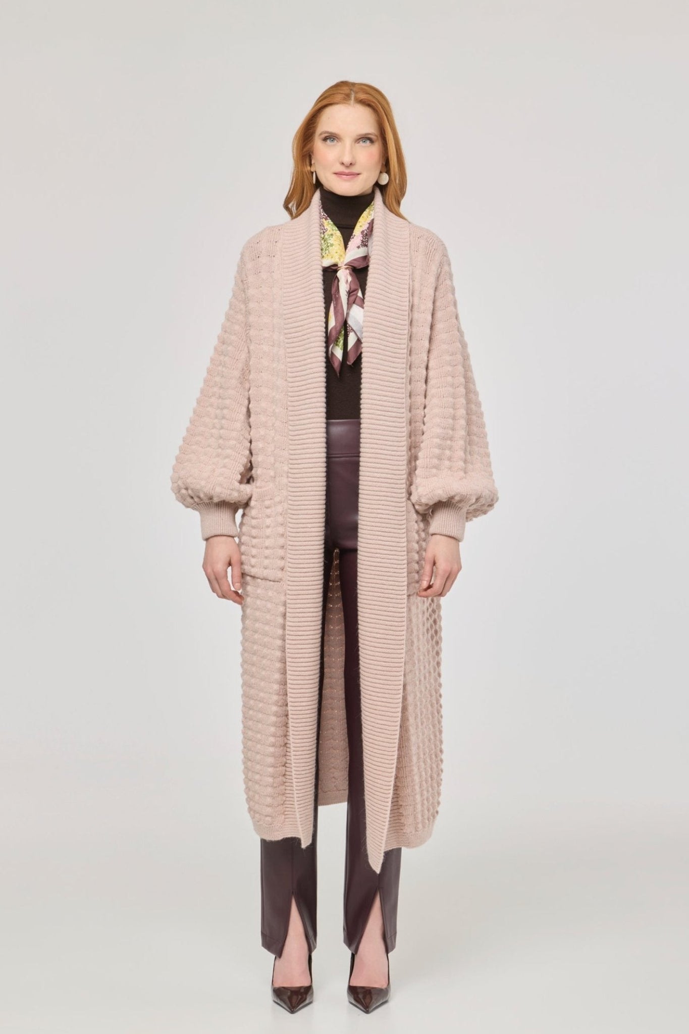 Cárdigan largo rosa de punto para mujer con mangas de textura geométrica y diseño minimalista.