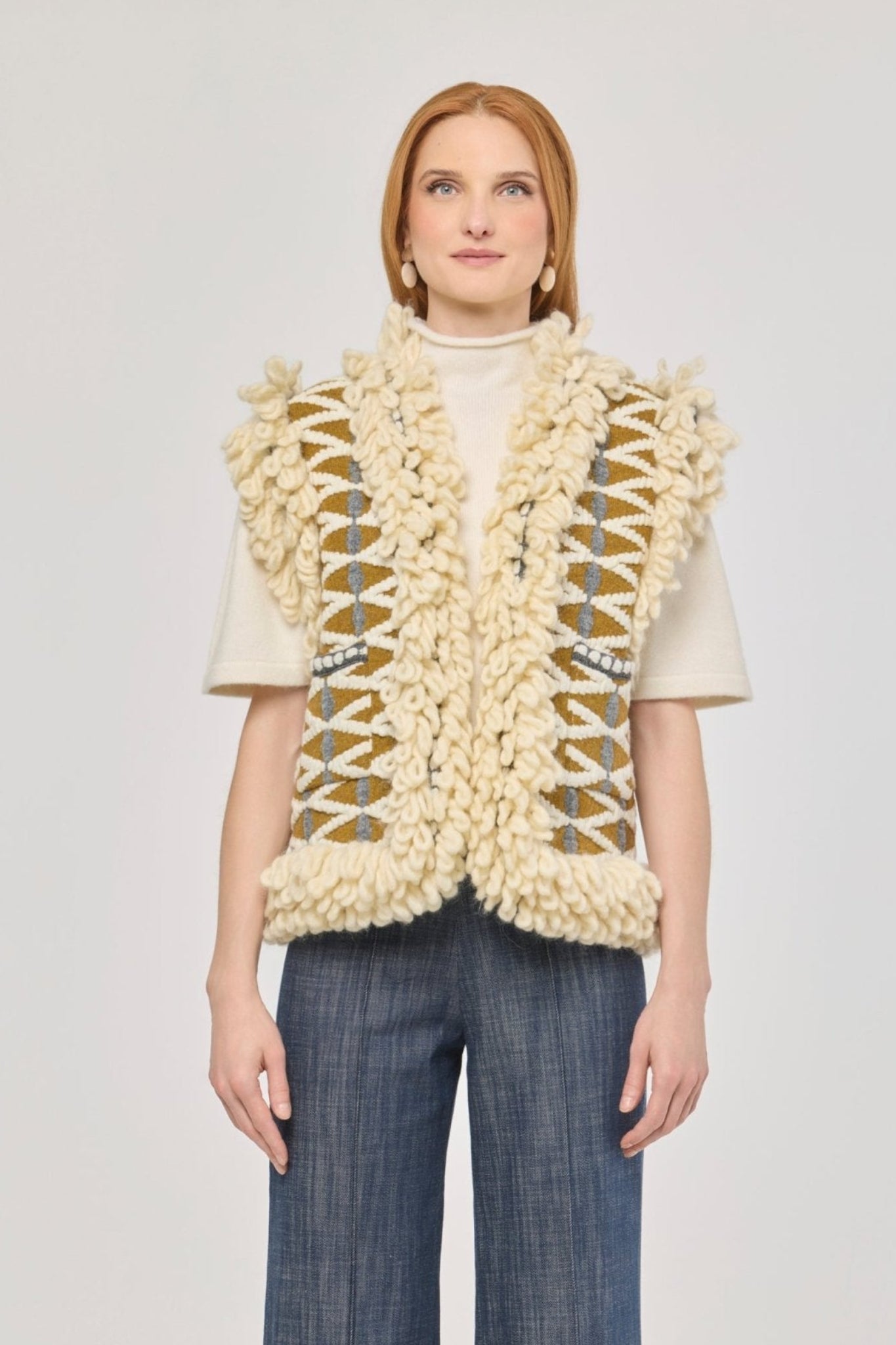 Chaleco de punto con flecos Brittany, diseño geométrico en tonos crudo y mostaza con acabado artesanal.