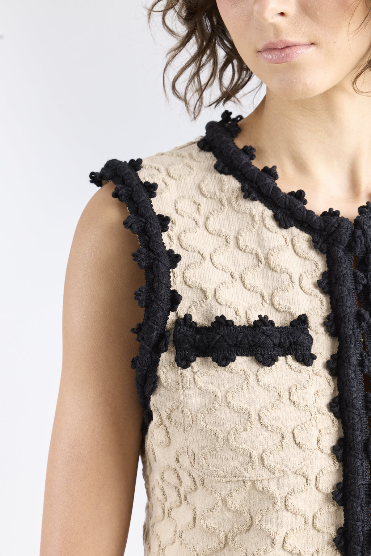 Chaleco de punto para mujer modelo Tristan en tono arena con bordados negros en relieve.