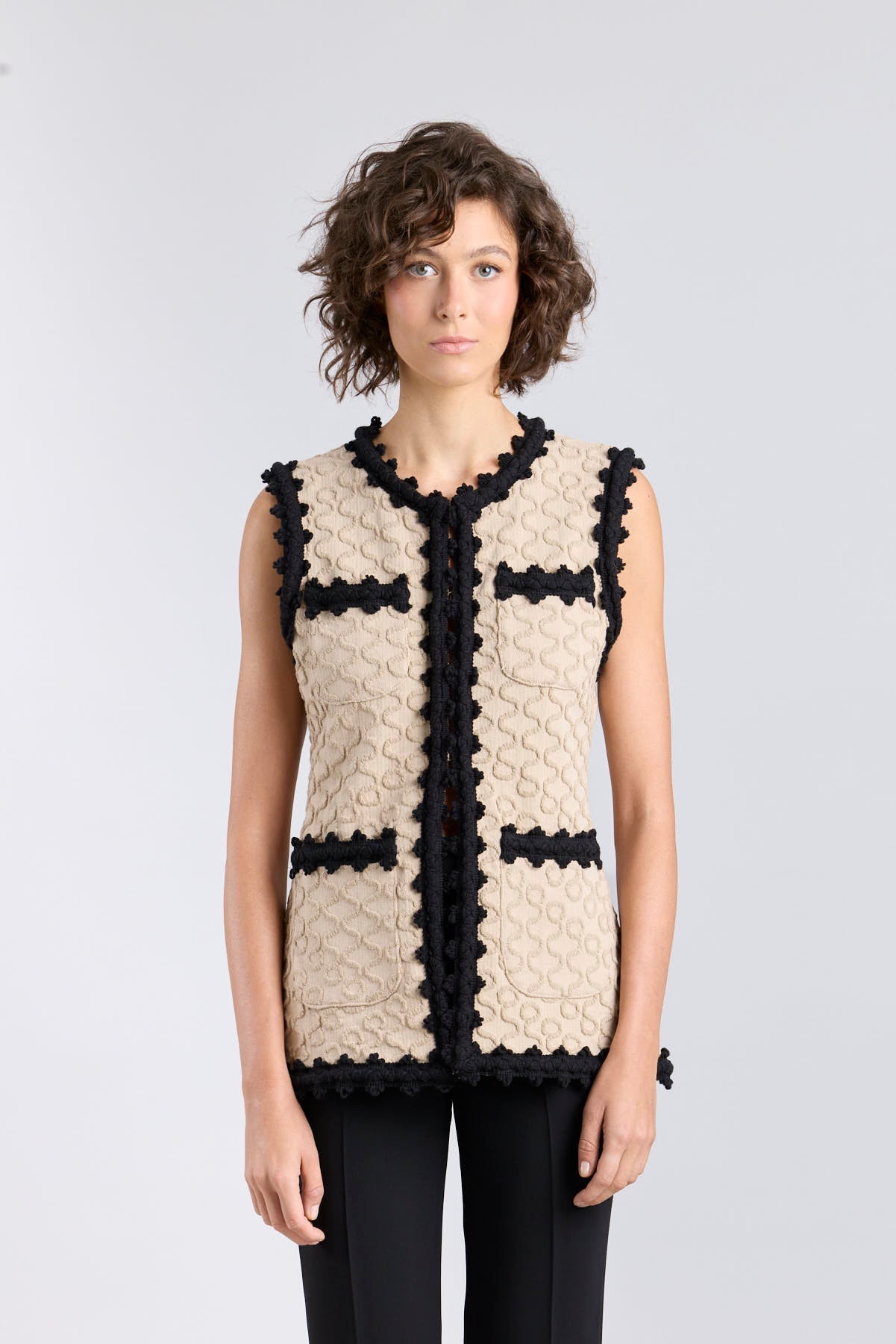 Chaleco de punto para mujer modelo Tristan en tono arena con bordados negros en relieve.