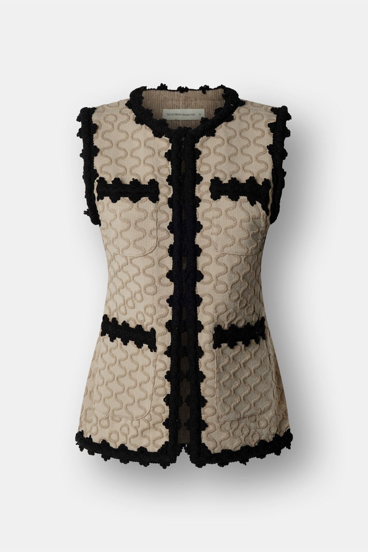 Chaleco de punto para mujer modelo Tristan en tono arena con bordados negros en relieve.