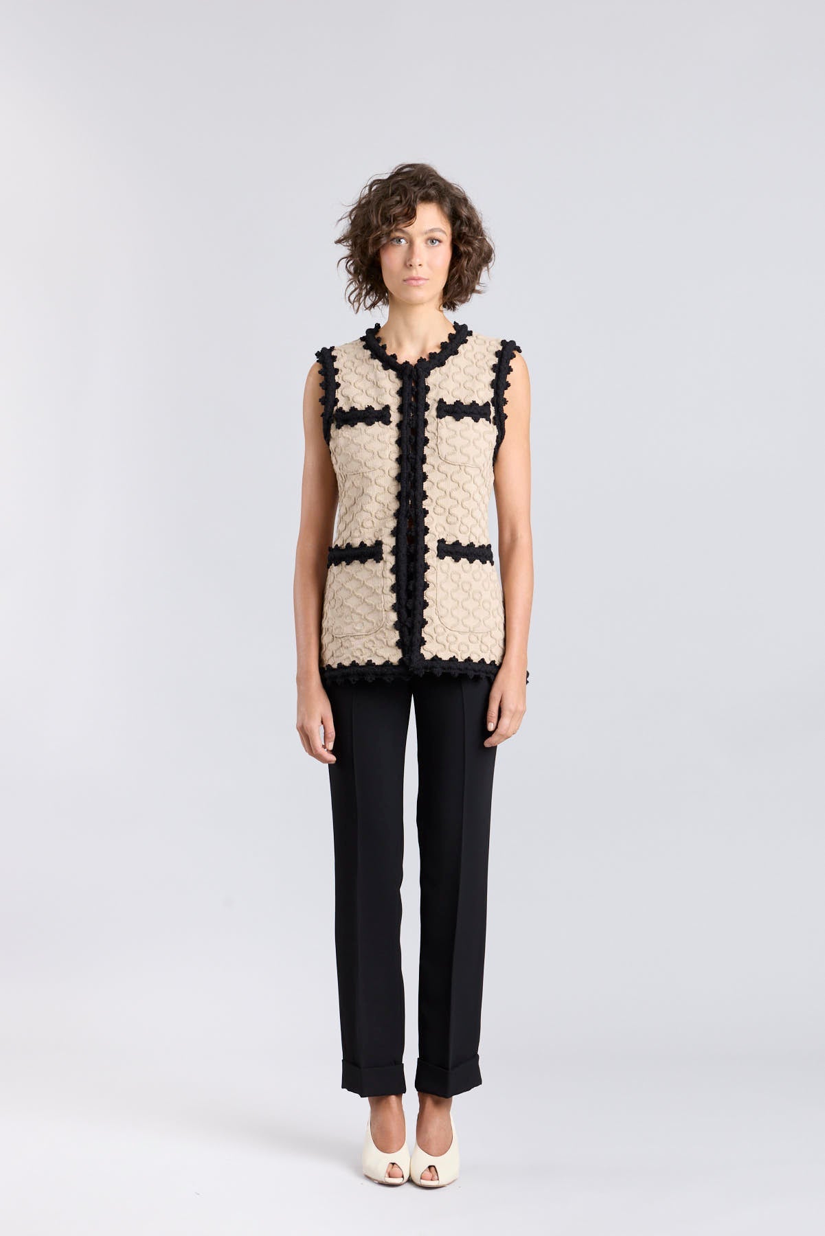 Chaleco de punto para mujer modelo Tristan en tono arena con bordados negros en relieve.