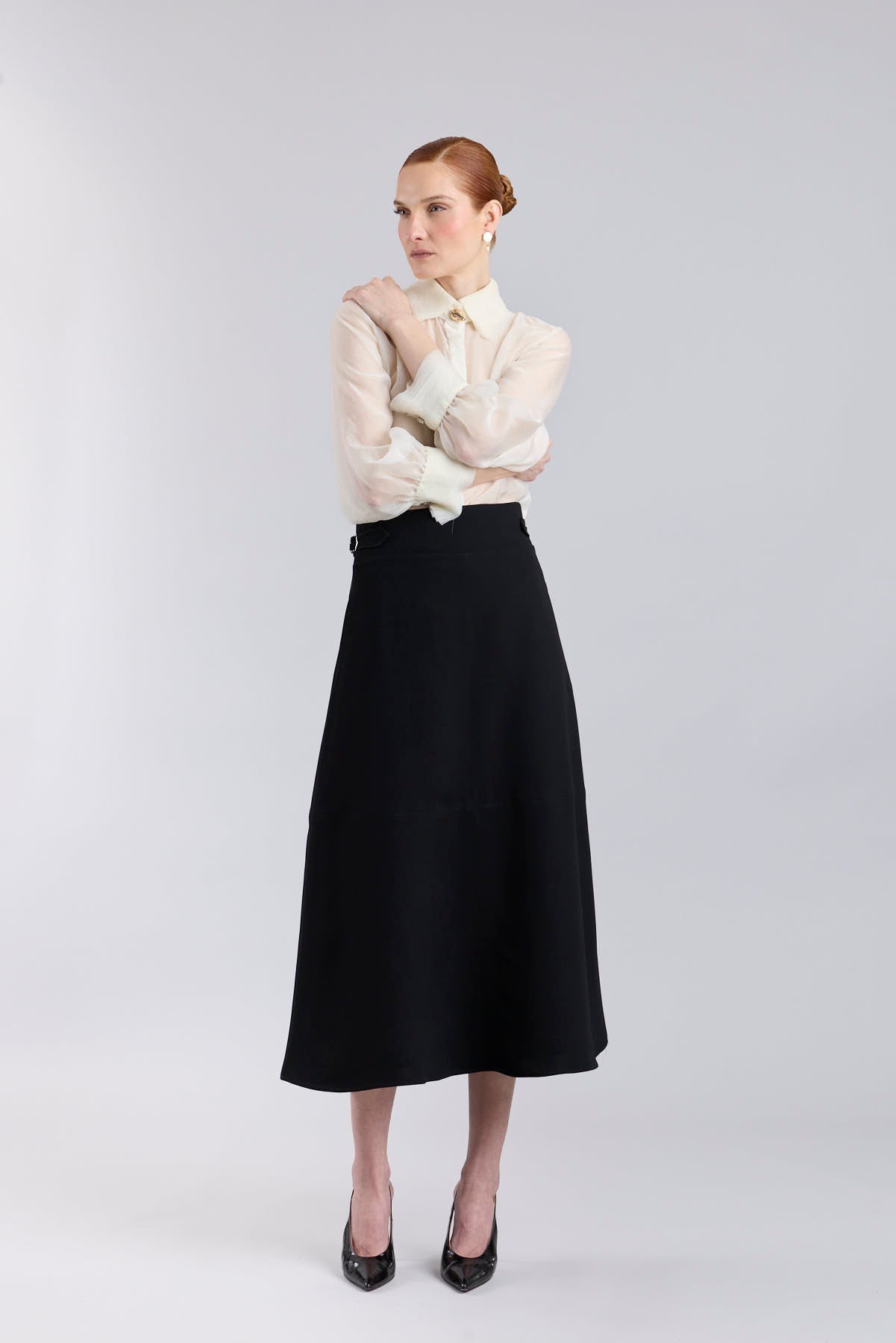 Falda midi de corte evasé color negro con detalle de hebillas en la cintura de The Extreme Collection.