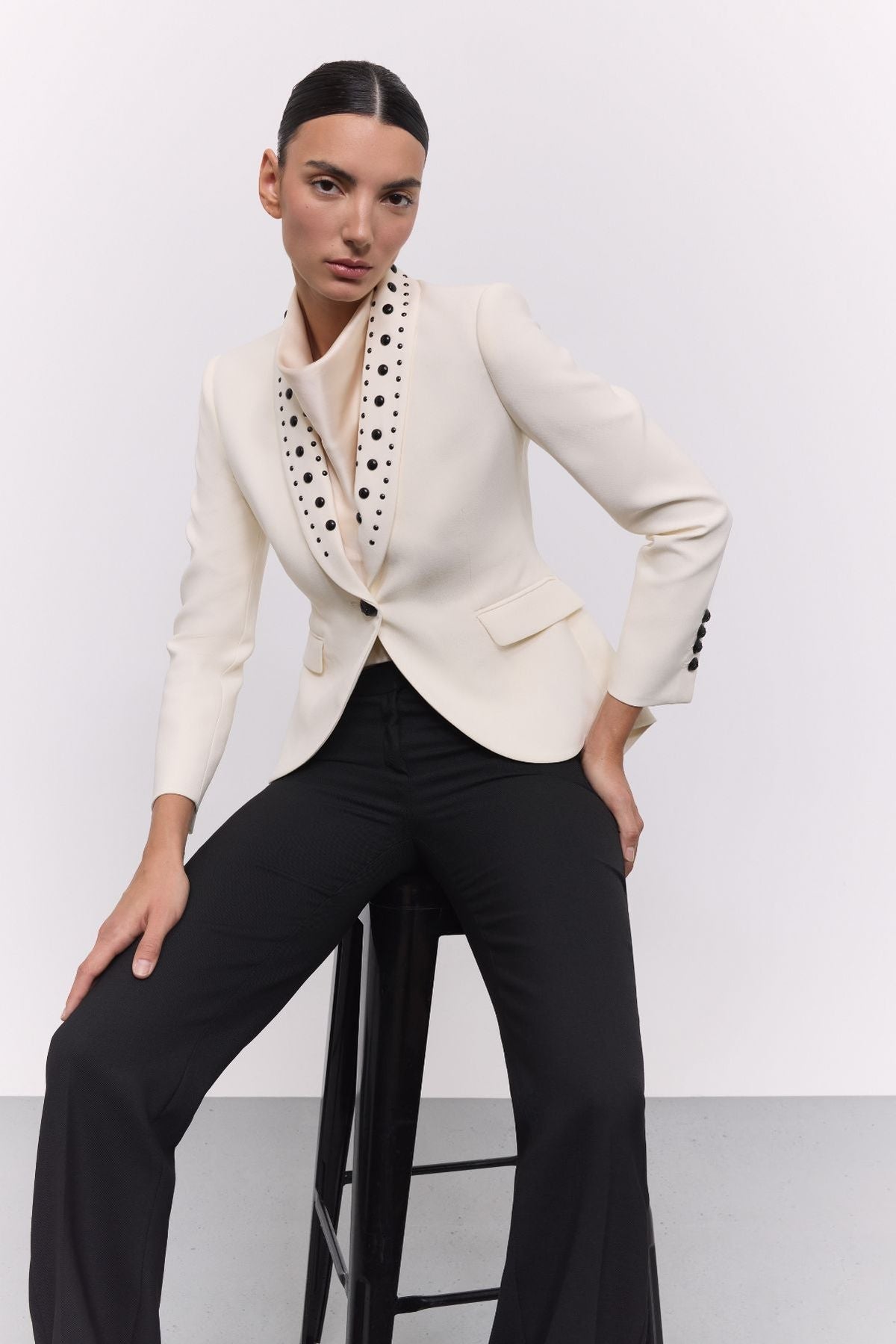 Blazer tachas marfil Eleanore en super crepe color marfil con solapa smoking, detalles de tachas negras colocadas a mano.