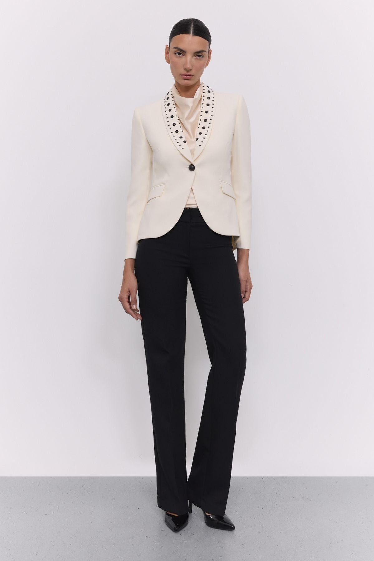 Blazer tachas marfil Eleanore en super crepe color marfil con solapa smoking, detalles de tachas negras colocadas a mano.