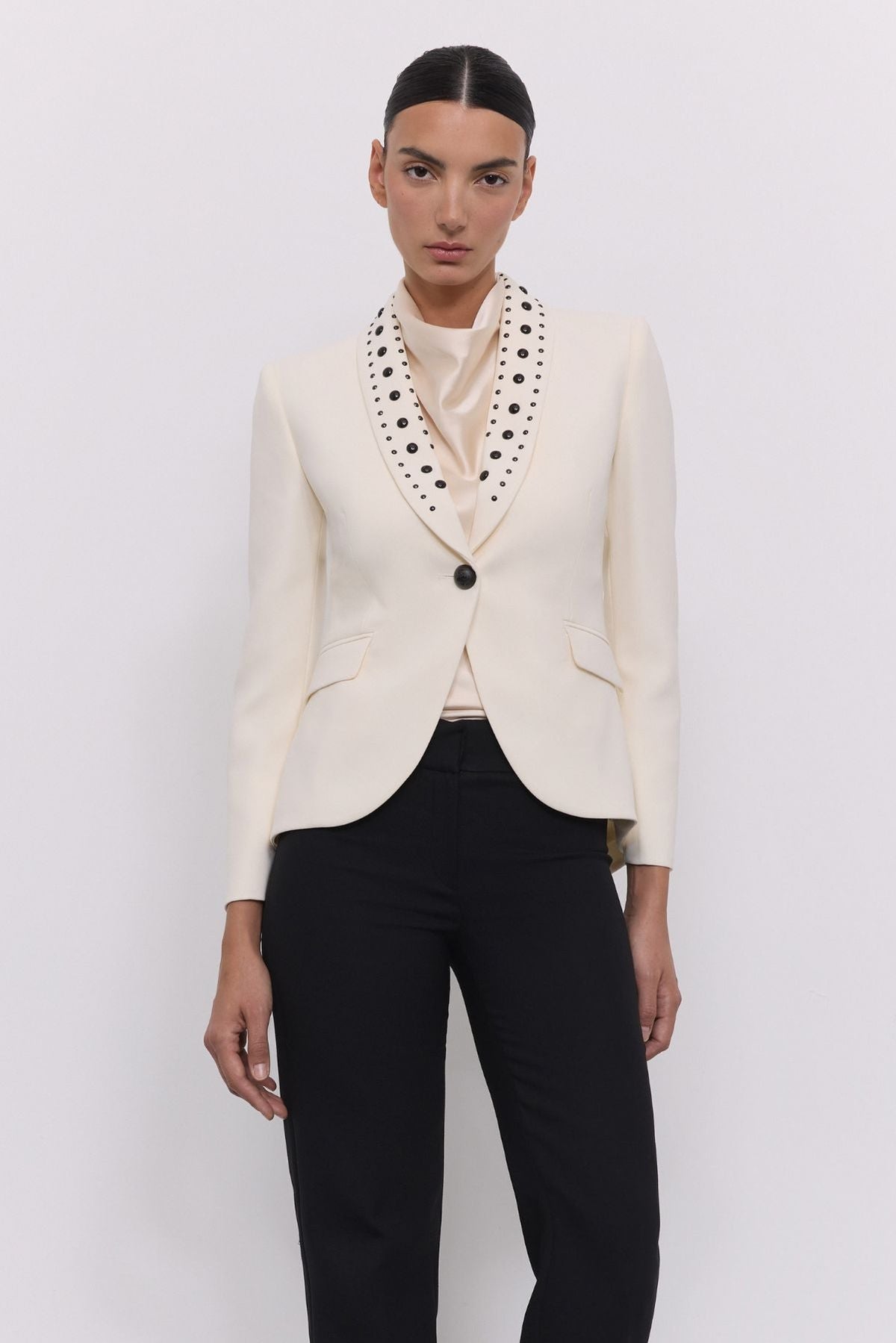 Blazer tachas marfil Eleanore en super crepe color marfil con solapa smoking, detalles de tachas negras colocadas a mano.