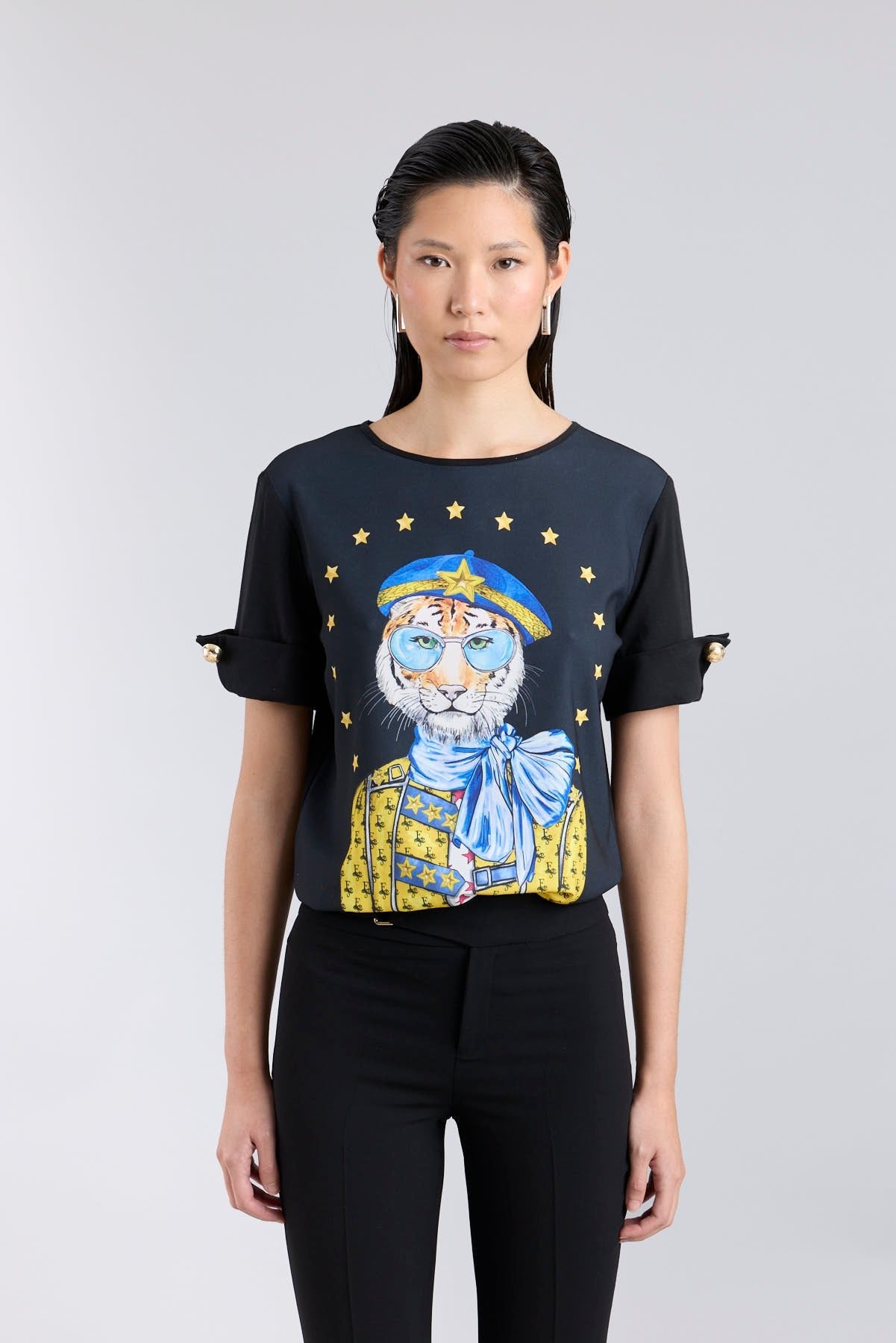 Camiseta negra con botones dorados en las mangas y estampado de tigre con boina azul de The Extreme Collection.