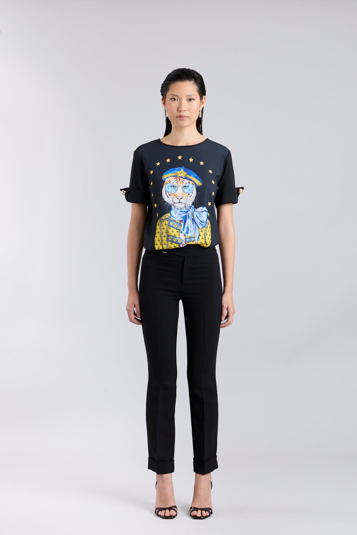 Camiseta negra con botones dorados en las mangas y estampado de tigre con boina azul de The Extreme Collection.