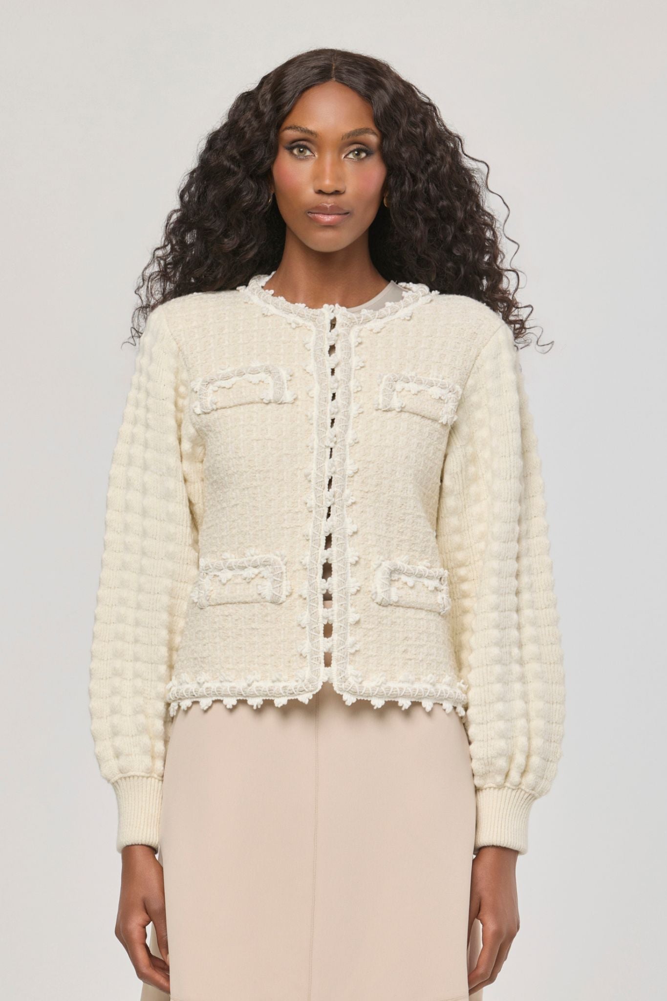 Cárdigan estructurado blanco de punto para mujer con estética estilo tweed, mangas abullonadas y ribetes detallados.