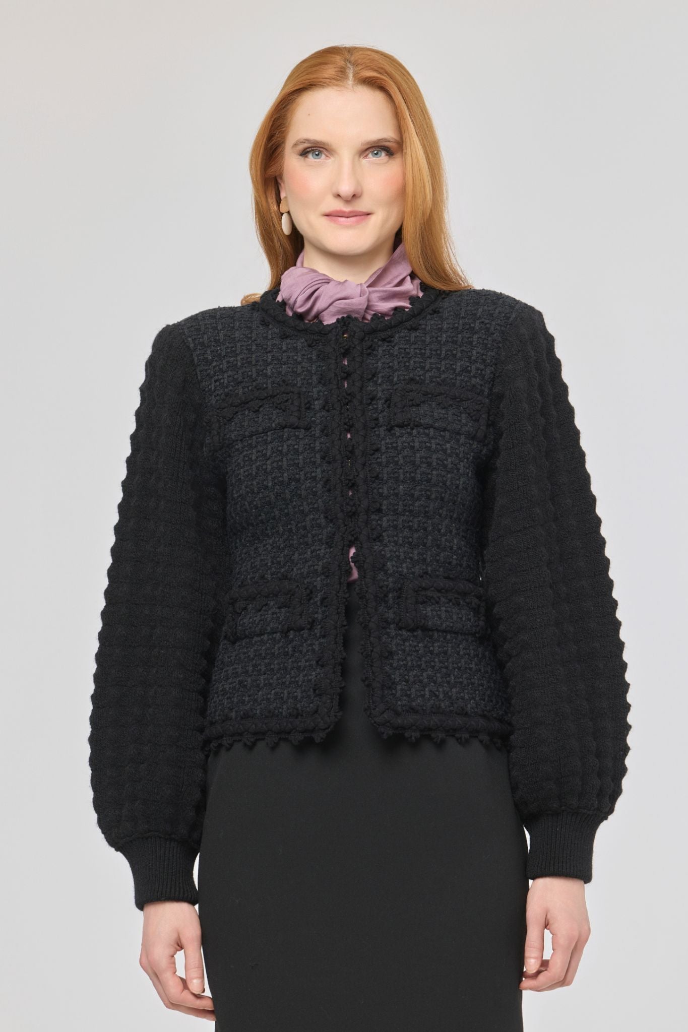 Cárdigan estructurado negro para mujer con estética estilo tweed, mangas abullonadas y cierre mediante corchetes.