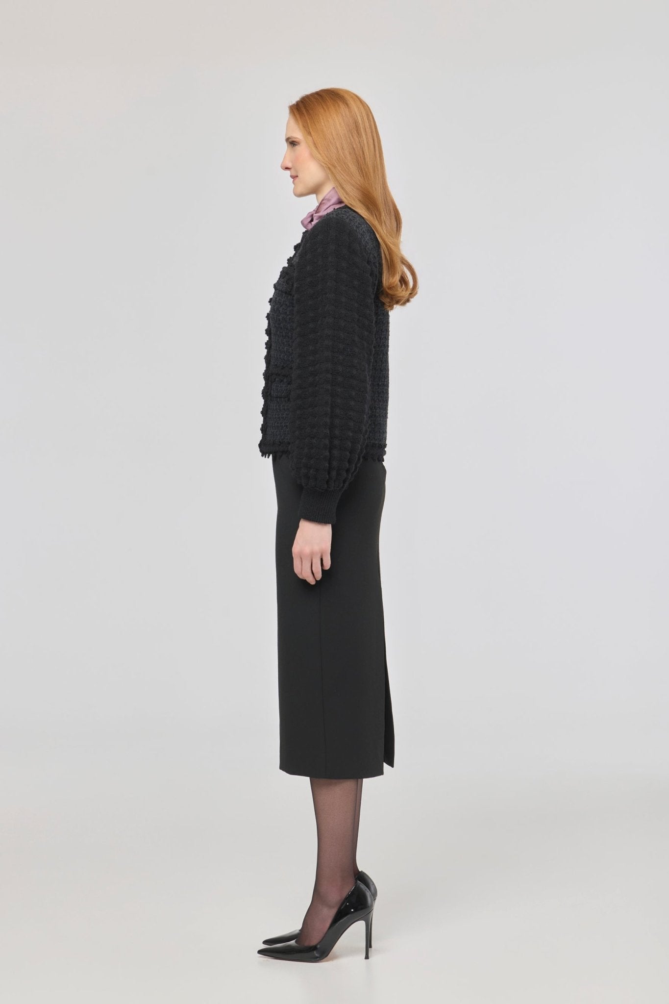 Cárdigan estructurado negro para mujer con estética estilo tweed, mangas abullonadas y cierre mediante corchetes.