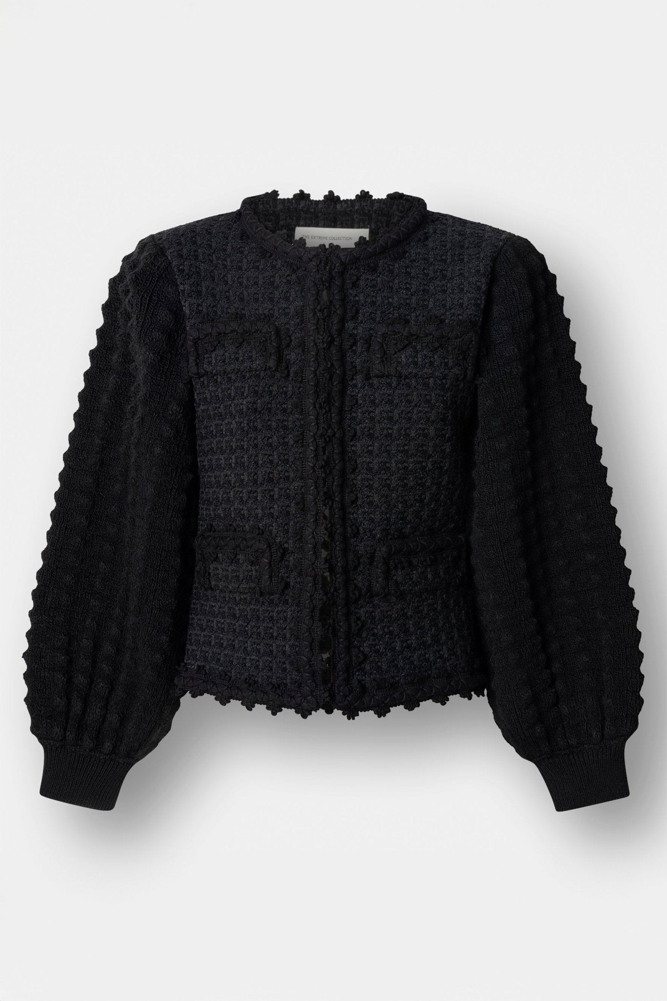 Cárdigan estructurado negro para mujer con estética estilo tweed, mangas abullonadas y cierre mediante corchetes.