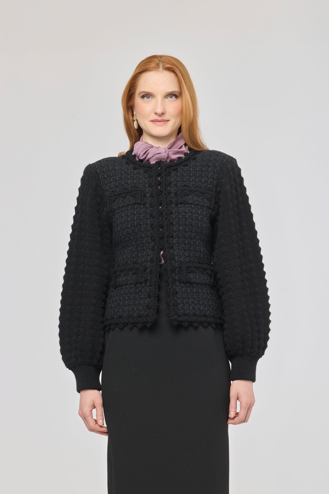 Cárdigan estructurado negro para mujer con estética estilo tweed, mangas abullonadas y cierre mediante corchetes.