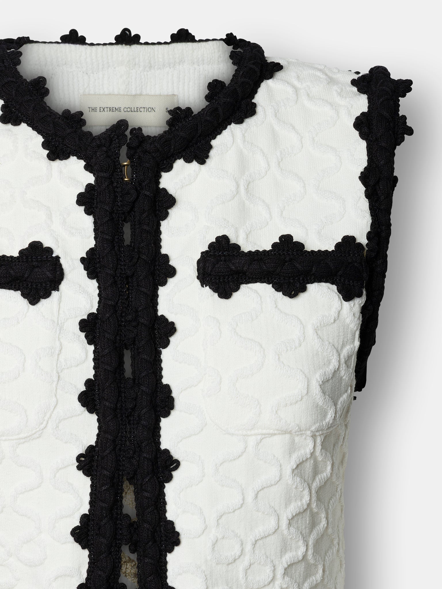 Chaleco de lujo blanco para mujer modelo Tristan con perfiles festoneados en negro.
