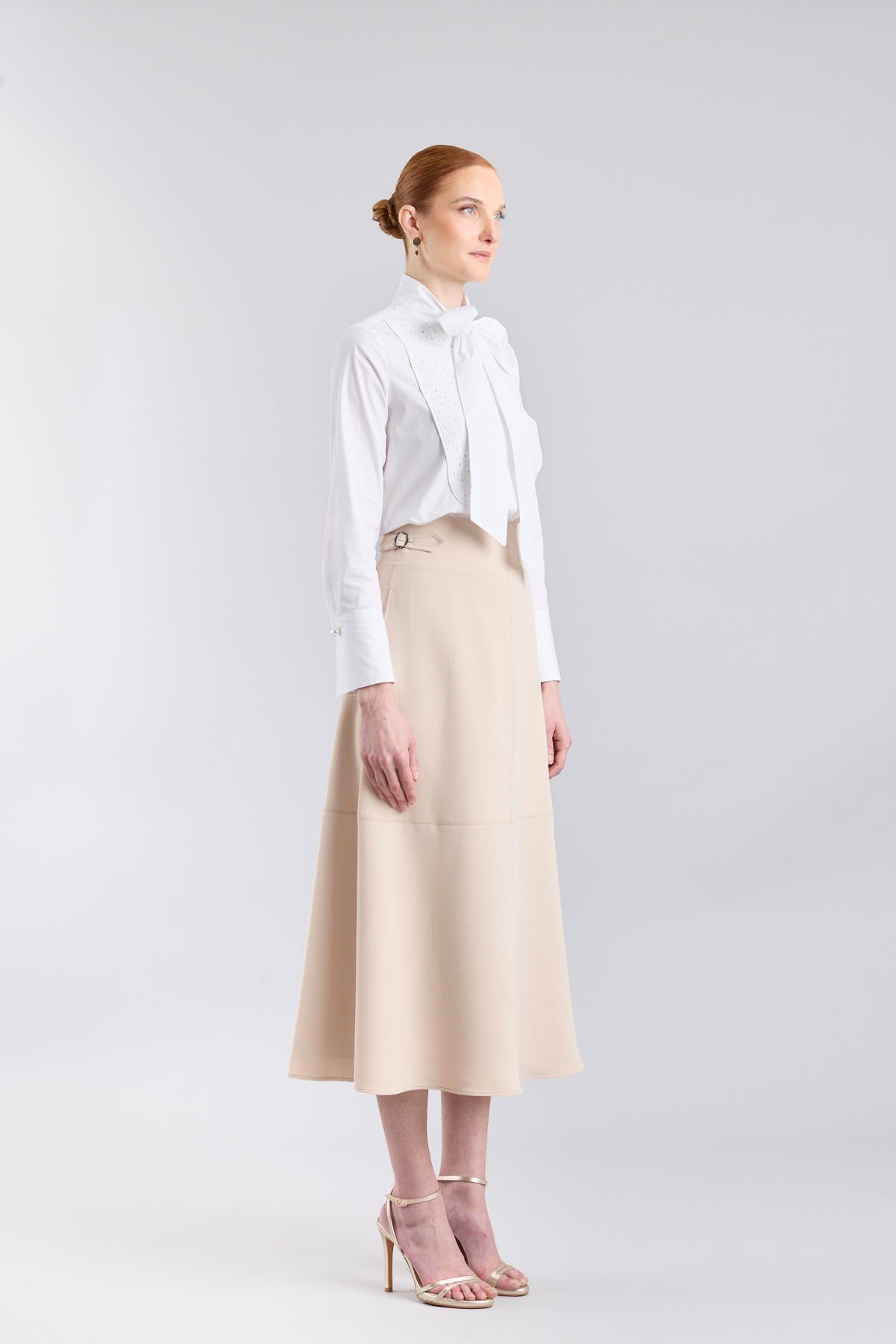 Falda midi de corte evasé color beige con detalle de hebillas en la cintura de The Extreme Collection.