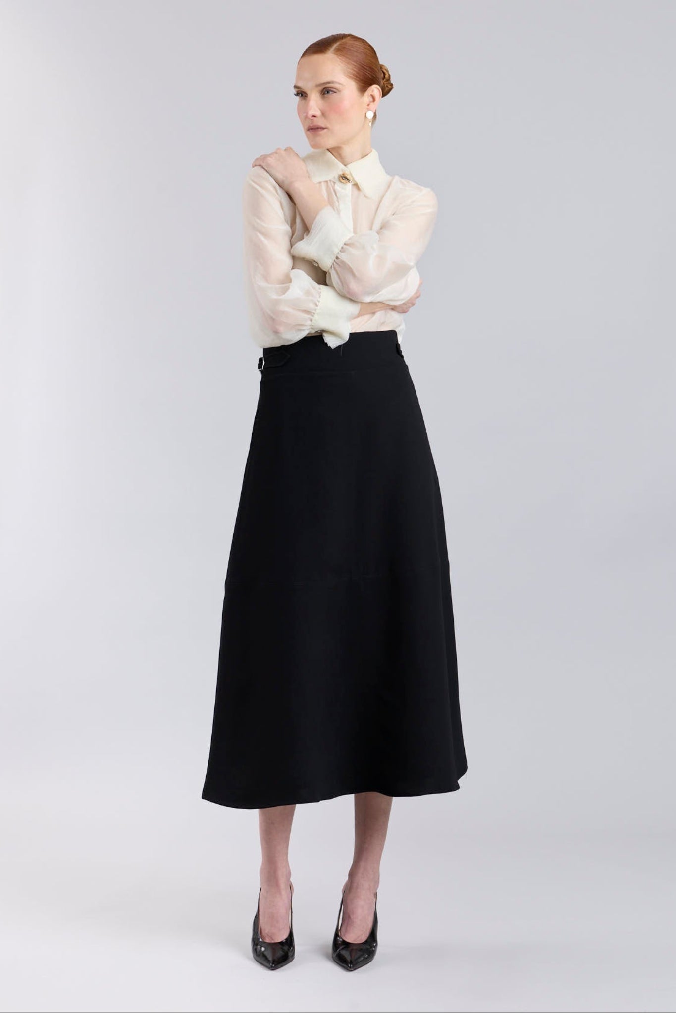 Falda midi de corte evasé color negro con detalle de hebillas en la cintura de The Extreme Collection.