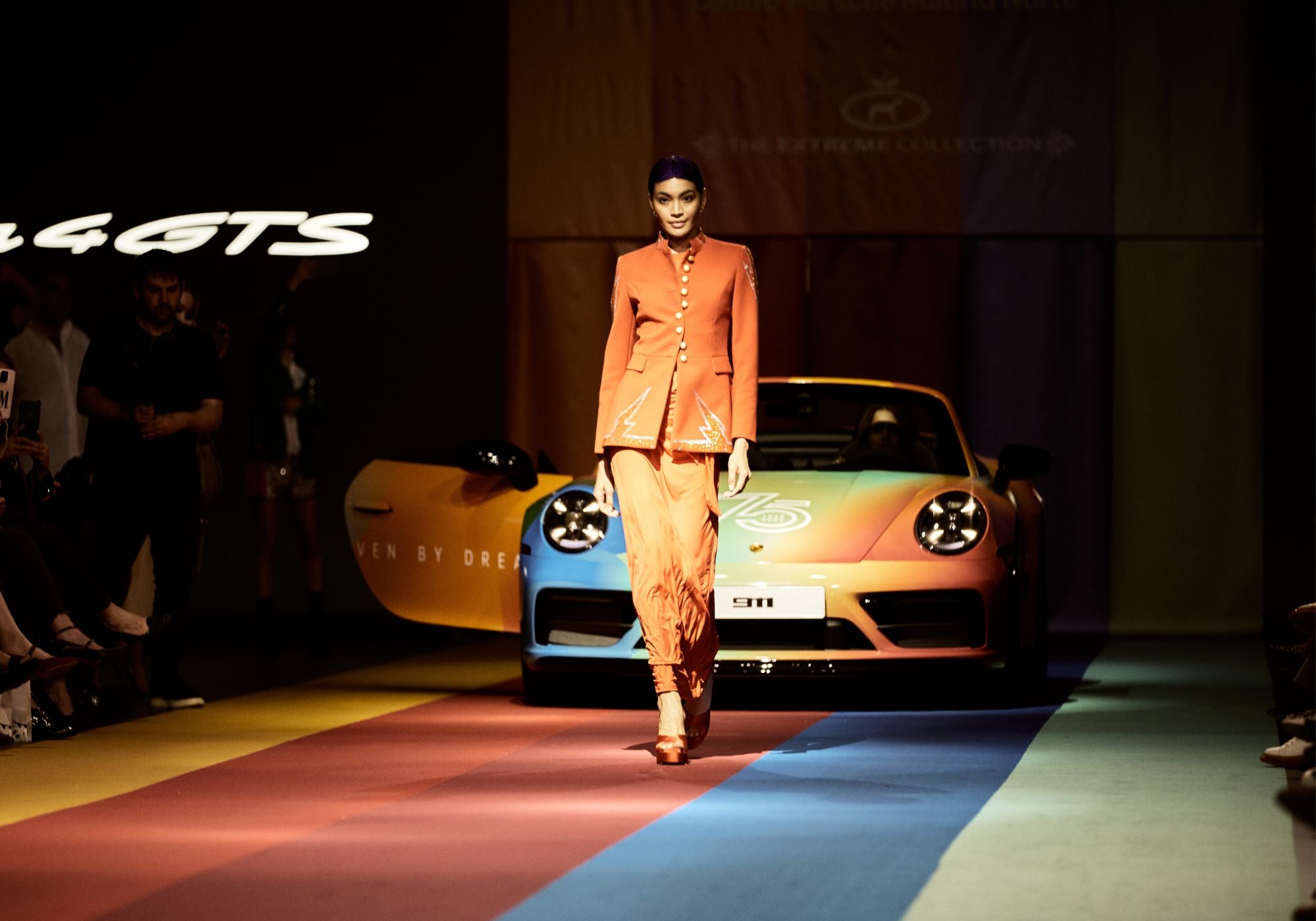 Modelo con chaqueta The Extreme Collection junto a un Porsche 911 clásico.